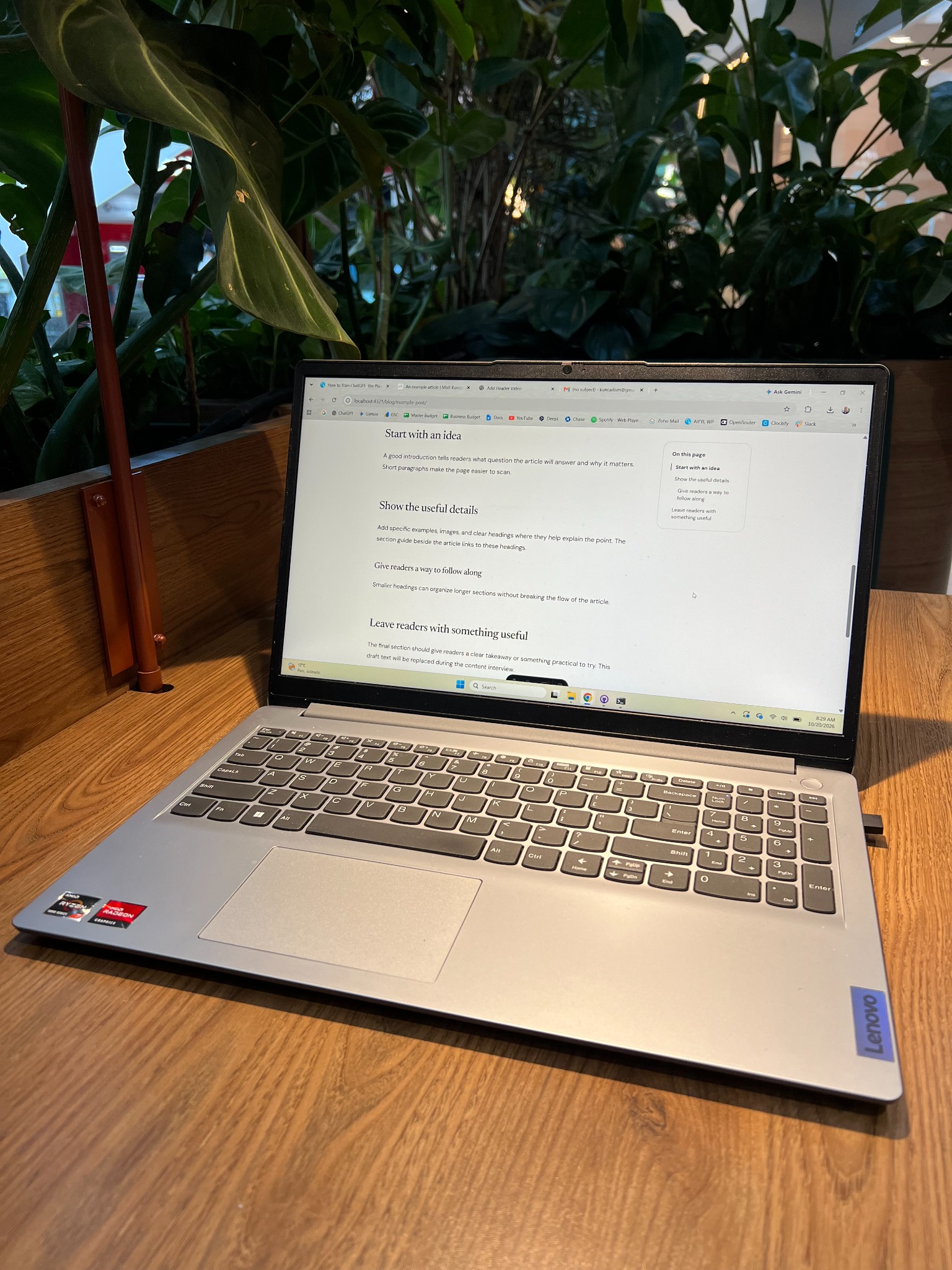 Laptop on a wooden table surrounded by green plants